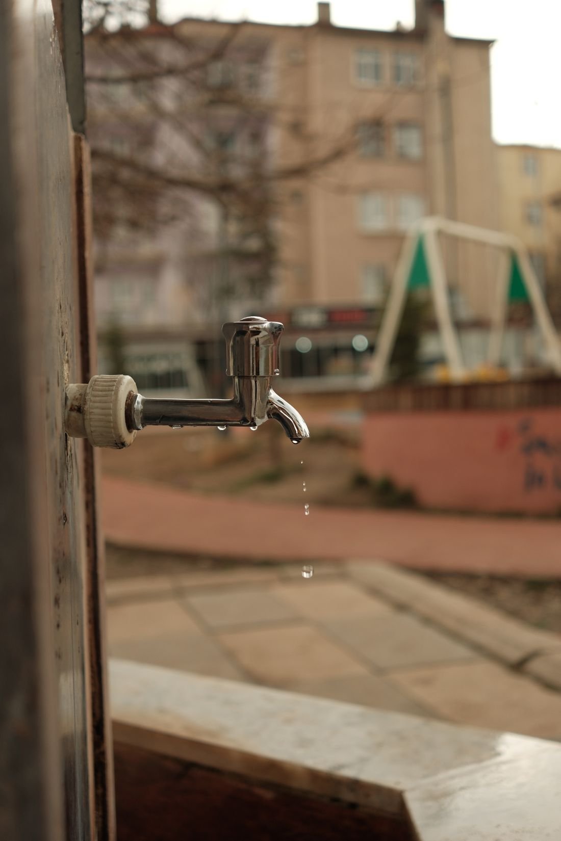 Llave de agua goteando en la pared exterior de una vivienda