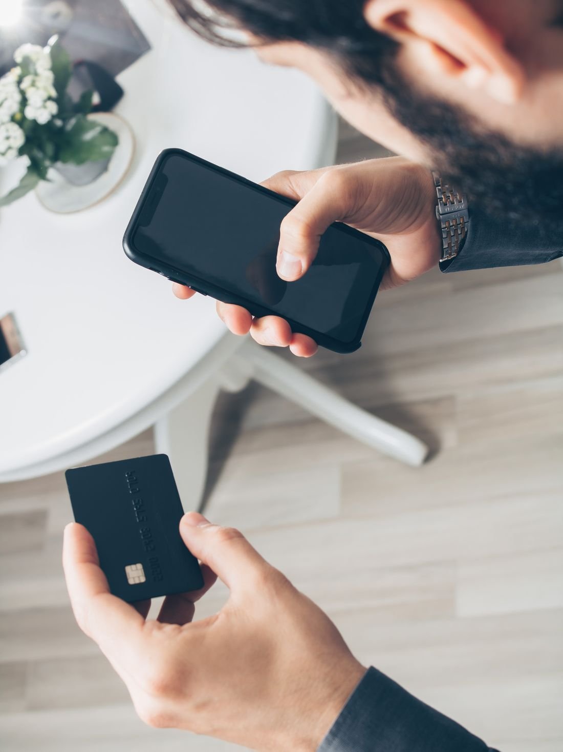 Persona sosteniendo un celular y una tarjeta bancaria para hacer un pago