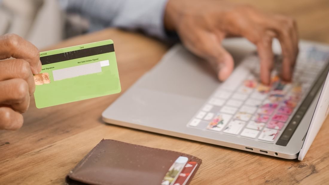 Persona con tarjeta de crédito frente a un computador