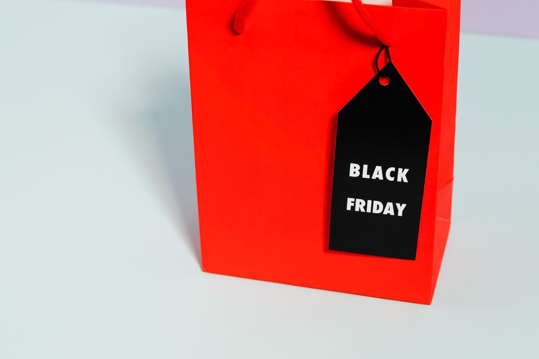 Bolsa de compras roja con una etiqueta negra que dice Black Friday sobre una mesa clara