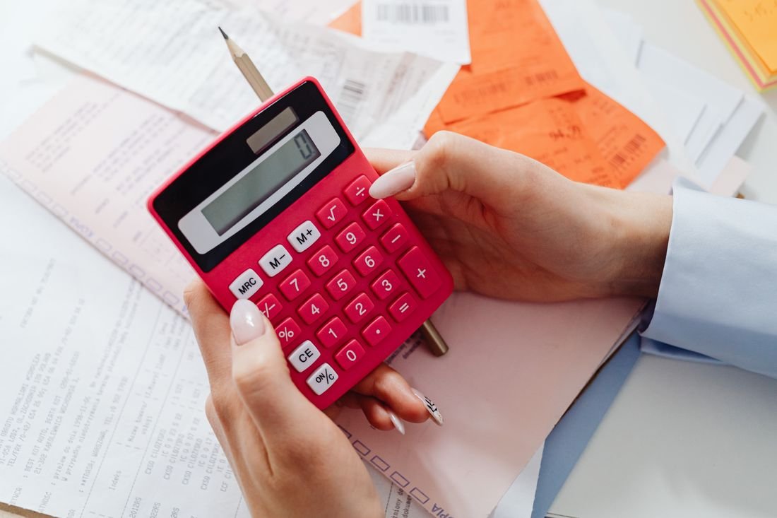 Persona revisando recibos y extractos con una calculadora roja en la mano