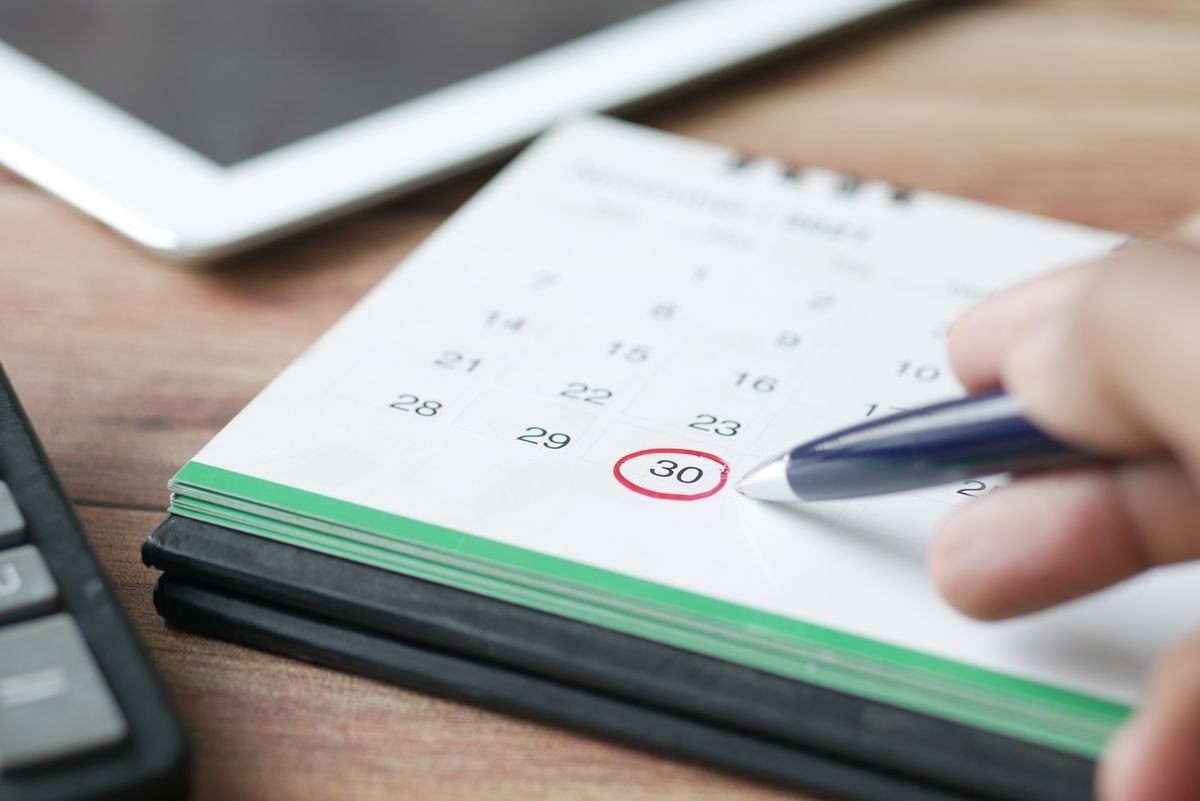 Mano marcando una fecha en un calendario con un bolígrafo