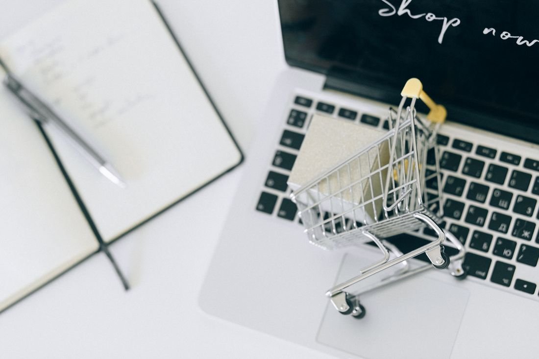 Carrito de compras en miniatura sobre el teclado de un computador portátil