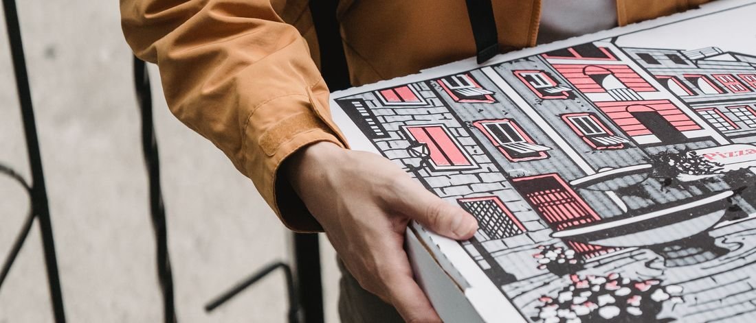 Repartidor con chaqueta llevando una caja de pizza en la calle