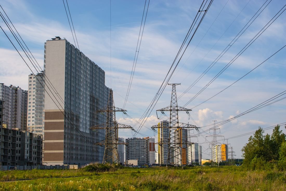 Torres de transmisión de energía y cables eléctricos frente a edificios de vivienda